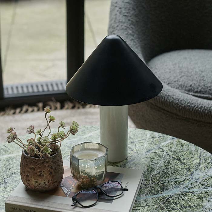 Black and white table lamp with cylindrical base and cone-shaped shade.