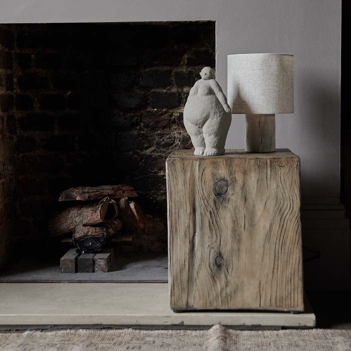 Grey figurative cement sculpture on a wood-effect side table.