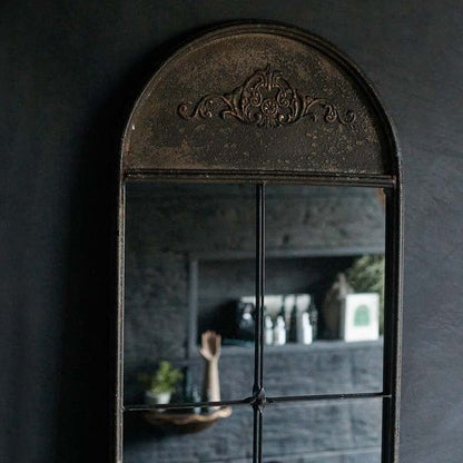 Decorative arched relief top of tall mirror.