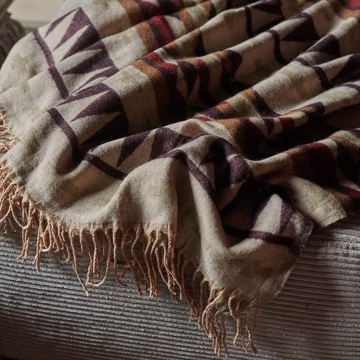 A closeup of the woven patterned of the Kensa Throw in purple and brown tones.
