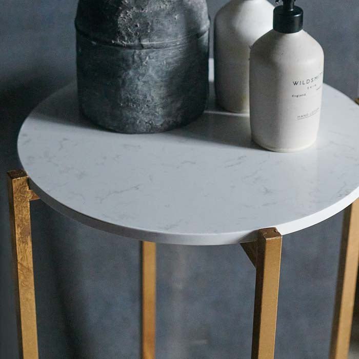 A closeup of the marble top of the Snowden Occasional Table, styled with a vase and some toiletries in grey and white tones.