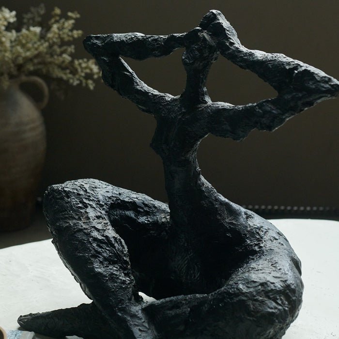 Resin sculpture of sitting figure, with rustic textured matte black finish. Sculpture in the home adds unique style to your home decor.