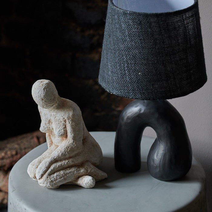 Black table lamp with sculptural ceramic base and black jute shade.