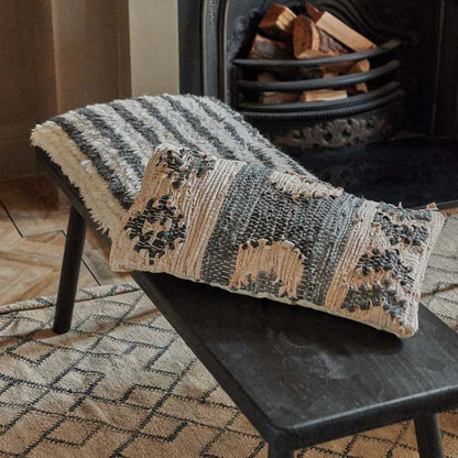 Long rectangular brown and grey patterned cushion on a black bench