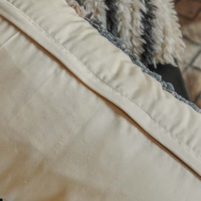 Cream back of a cushion with fabric covering a zip
