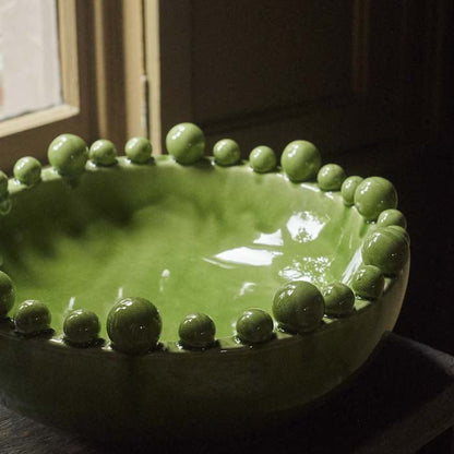 Glossy green glaze on a large ceramic bowl with a decorative rim
