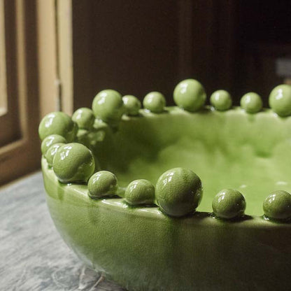 Varying ball shapes attached the rim of a large green bowl