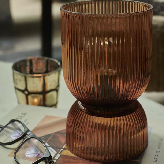 Hourglass shaped led lamp in an amber glass sat on a coffee table book