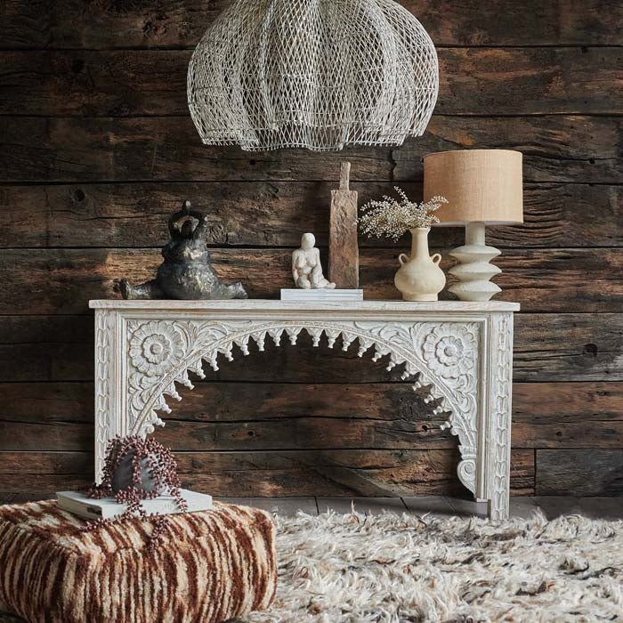 Karnata Carved Console, a slim wooden console with an elaborately carved arched front design, with oversized pendant shade.