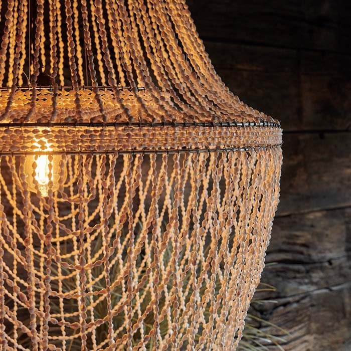 A closeup of the warmly lit Montauk Pendant showing the detailing of the tiny delicate shells from which it is made.