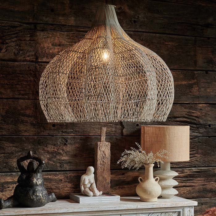 The Sarria Rattan Pendant, a stunning oversized whitewashed rattan pendant shade in a room with rustic wooden walls.