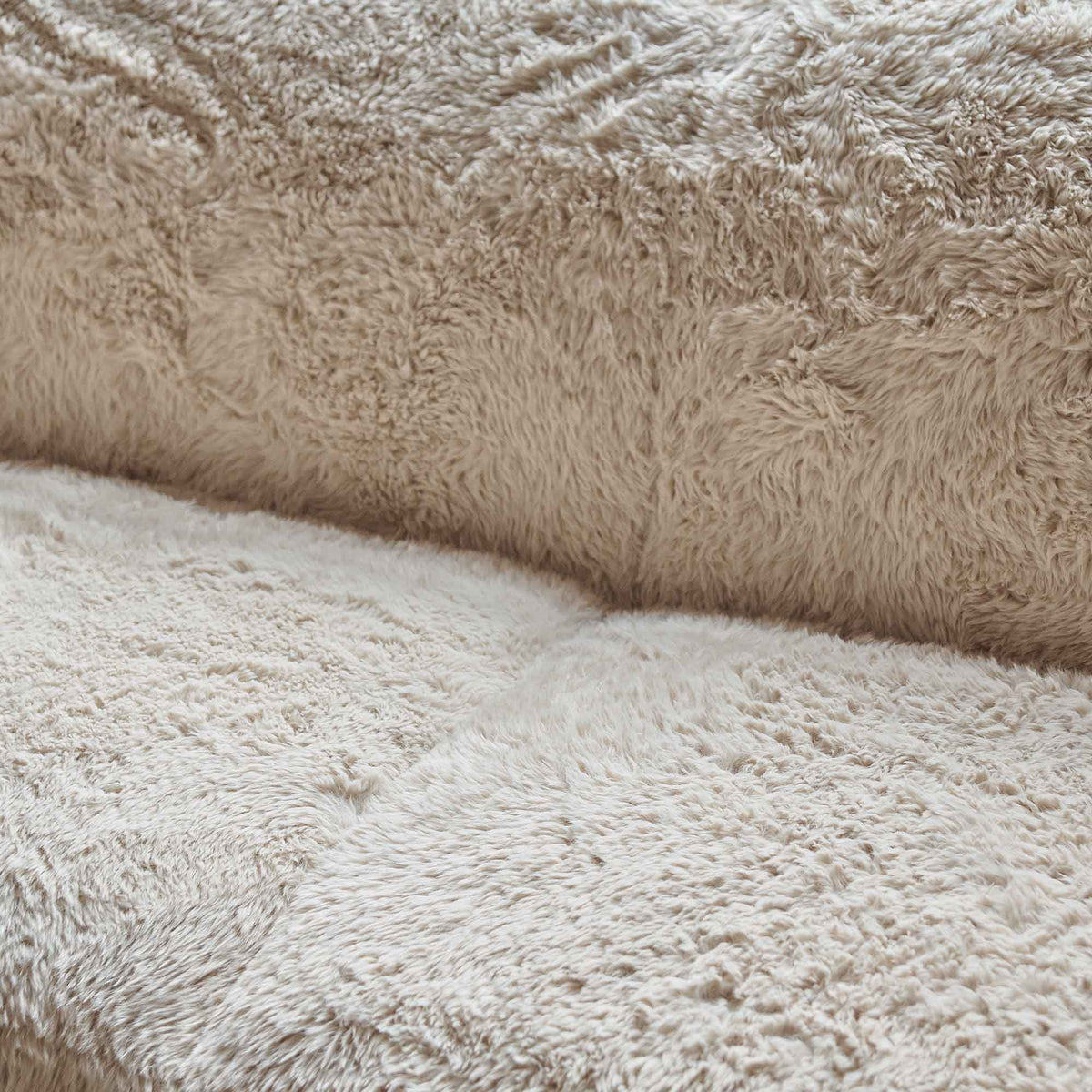 A closeup of the soft cream faux fur upholstery of the Saskia Sofa.