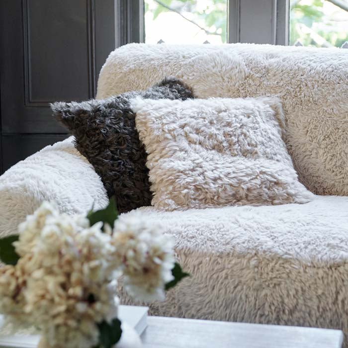 Shaggy cream sheepskin cushion on a faux fur couch