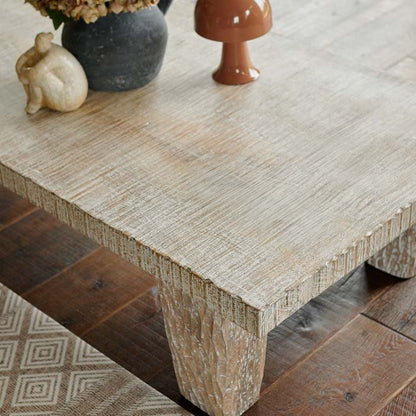 Detail image of the carved texture of a pale wooden coffee table.