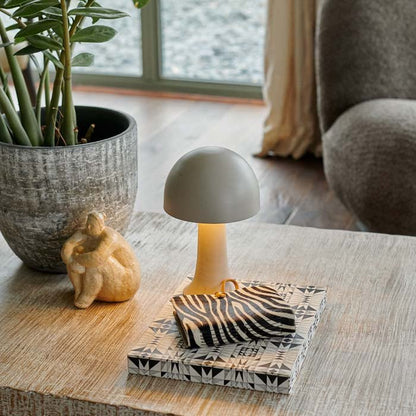 A small metal curvaceaous mushroom shaped lamp in a light neutral colour by Abigail Ahern, known for her rule breaking designs and stylish interiors. Styled on a coffee table with some books, a houseplant, these small but mighty curvy lamps are super flexible to pop all over the house, style next to your bath, bedside or create intrigue to your tablescapes and a dash of colour to your kitchen worktops.
