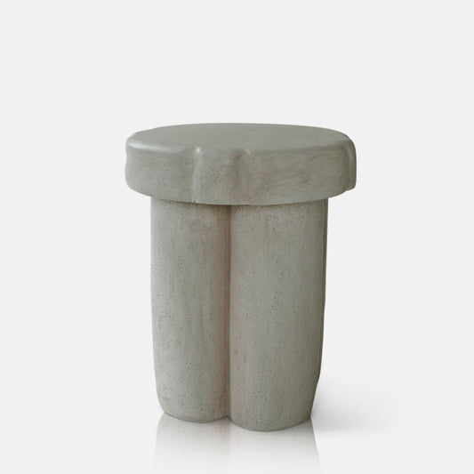 Cutout image on a white background of a cream side table. The side table has an abstract, curved style and a smooth finish.