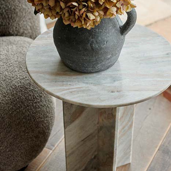 The Tortona Side Table, next to an olive coloured boucle chair, with a grey cement jug and some mustard coloured stems.