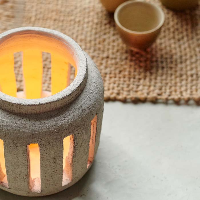 Detail shot of our stoneware candle lantern with a lit candle inside, emitting a soft cosy glow.