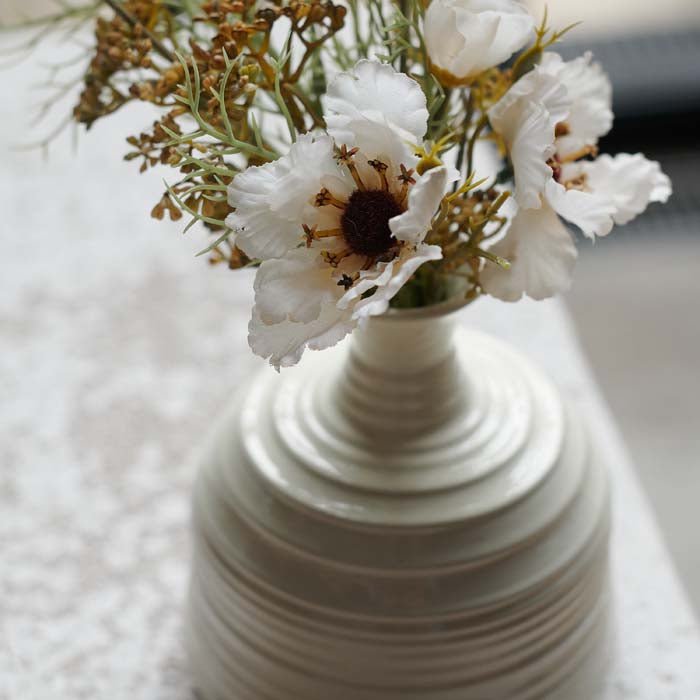 Detail image of a small, ribbed white vase with some of Abigail Ahern's bestselling artificial flowers.