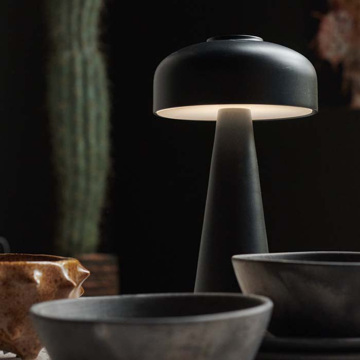 Detail image of the curved dome top and modern base of a black rechargeable table lamp.
