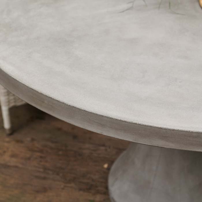 A closeup showing the grey cement surface of the Datura Round Dining Table.