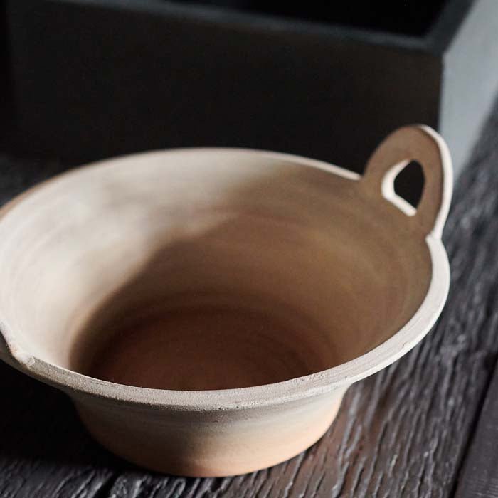 A close up of the Lucerne Terracotta Bowl. A traditional rustic terracotta bowl with handles styled with some brown napkins.