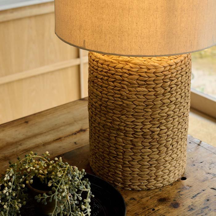 The Celano Rope Table Lamp, a cylindrical table lamp with a chunky knotted base and a natural coloured drum shade.