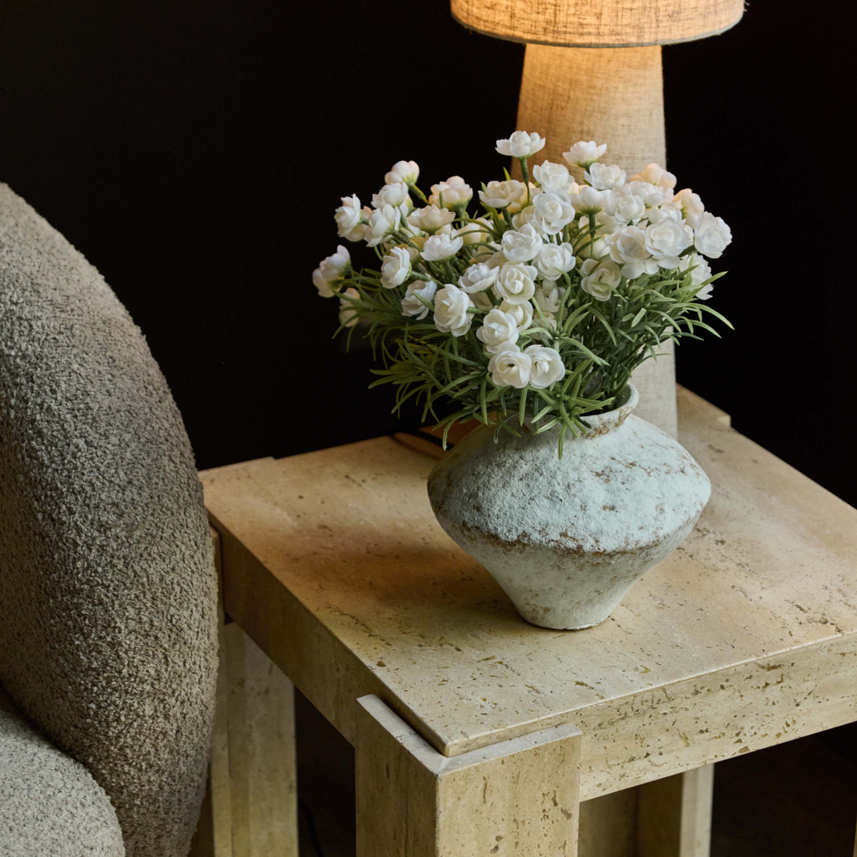 Abigail Ahern Santa Travertine Side Table featuring a soft cream stone finish and rounded contemporary shape, adding understated elegance to a modern living room.