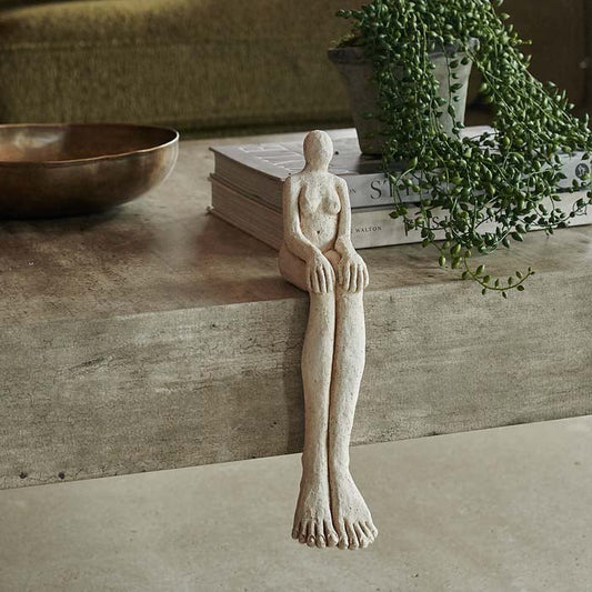 Ceramic sculpture of a female figure with a slightly abstract form and dramatically elongated and enlarged legs.