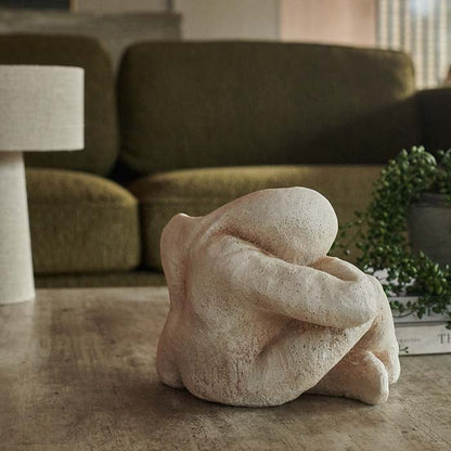 Sitting figurine crafted from cement, on a concrete-look coffee table.