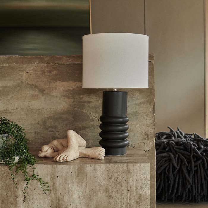 Table lamp with white shade and black base, displayed on concrete-look sideboard.