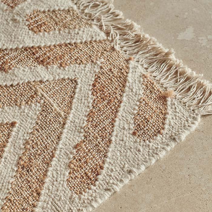 Tasseled edge of a woven cream and brown cotton, jute and wool rug.
