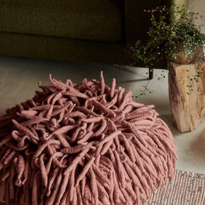 Rust-pink shaggy wool floor pouffe.
