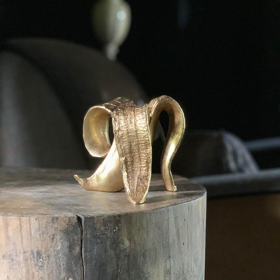 The Golden Banana Candleholder, a quirky candleholder made from resin and finished in gold in the shape of a peeled banana.