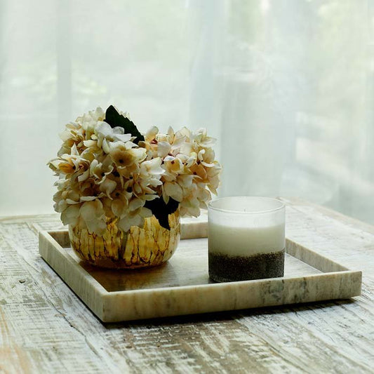 Stunning, pale marble tray with a precise square shape. Styled with a small metallic vase of faux flowers and a candle.