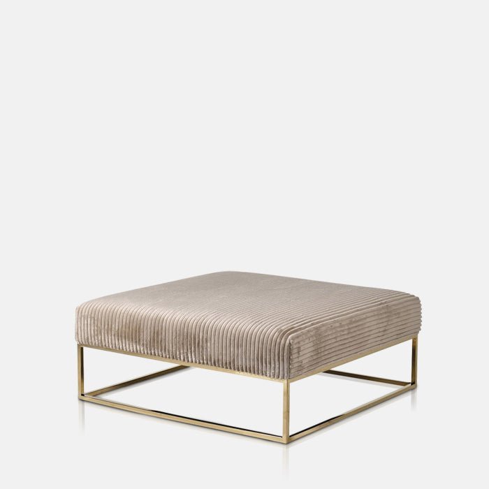 A cutout of the Andover Ottoman. A square coffee table upholstered in a soft brown corduroy velvet with a brass colour frame.