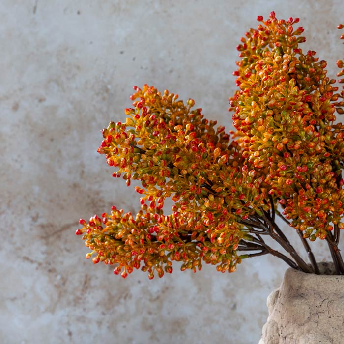 Detail image of the textural heads on some vibrant orange artificial sorghum stems.