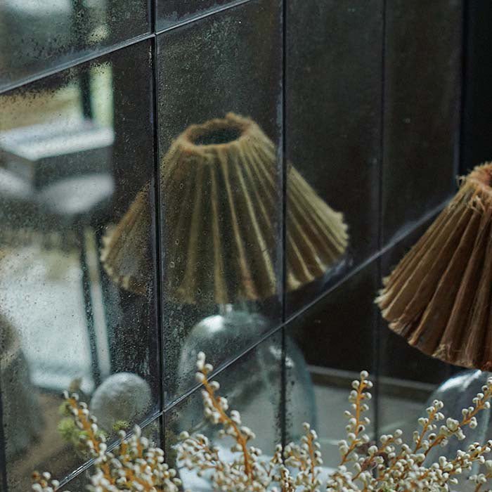 A glass lamp reflected in a window pane section of the Aslan Mirror.