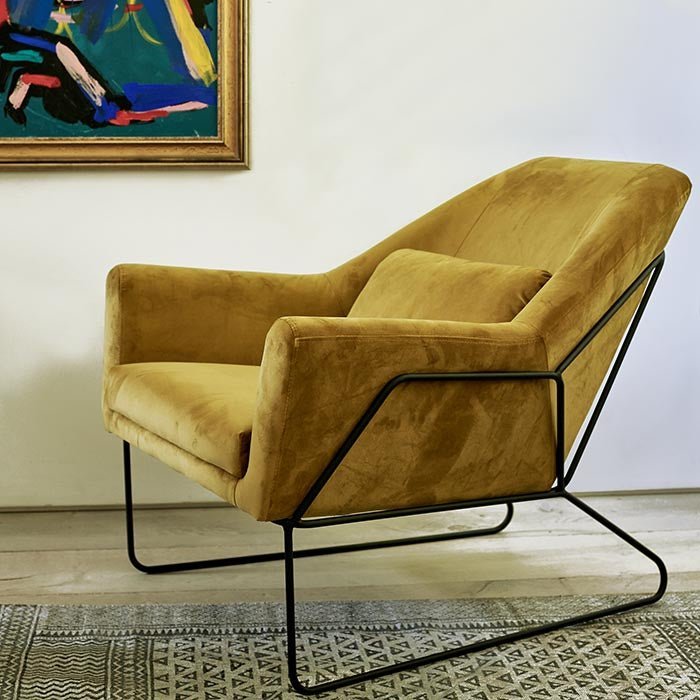 The Atura Occasional Chair, a large angular yellow velvet armchair with a black metal frame and metal legs.