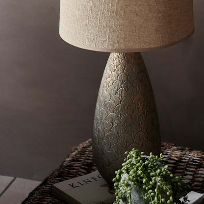 Engraved fishtail patterned table lamp base in bronzed metal finish.