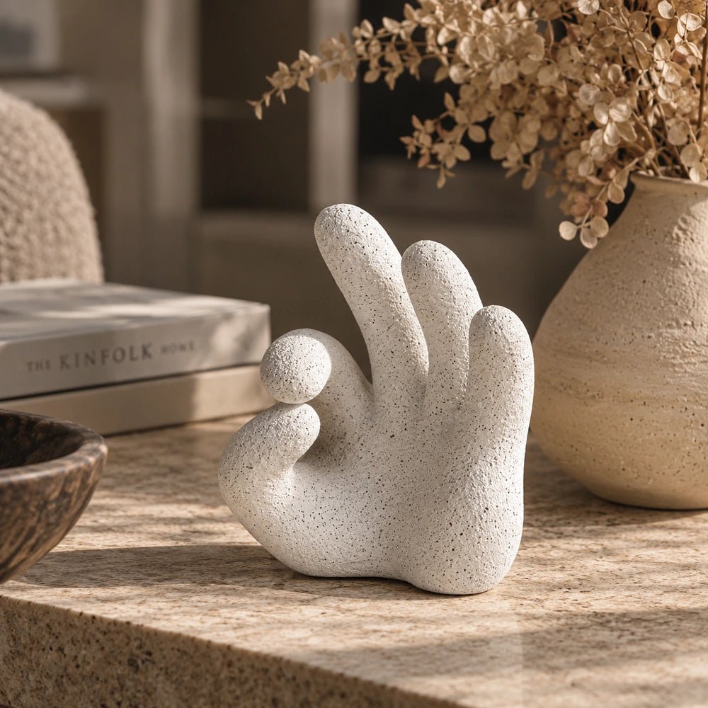 Ballo Hand Sculpture with expressive hand-shaped form, styled on a coffee table in a warm contemporary living room with layered neutral decor.