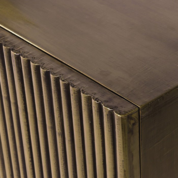 Close-up of the Abigail Ahern Banbury Sideboard highlighting its textured antique brass finish and subtle warm gold tones with ribbed gold doors on a long gold cabinet.