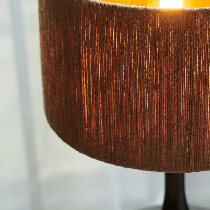 A close up of the Brooklyn Table Lamp. A sculptural black curvy table lamp in mango wood with a natural jute shade.