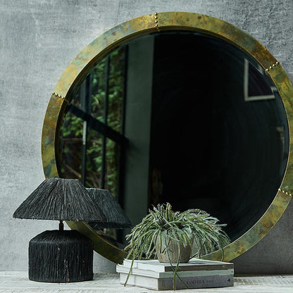 Large round mirror with an antique gold frame leaning against a wall on a console