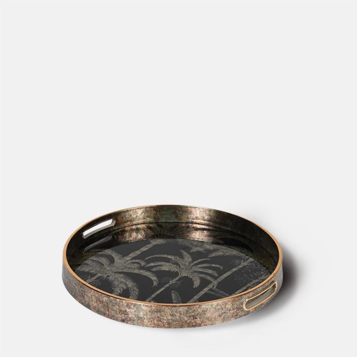The Cayman Tray, a round tray with gold handles and a palm tree design in antique gold on black.