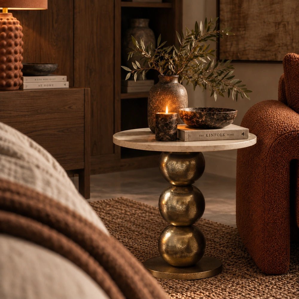 Chelsea Marble Side Table styled between upholstered seating, with books, a candle and vase arranged on its round top in a warm living room.