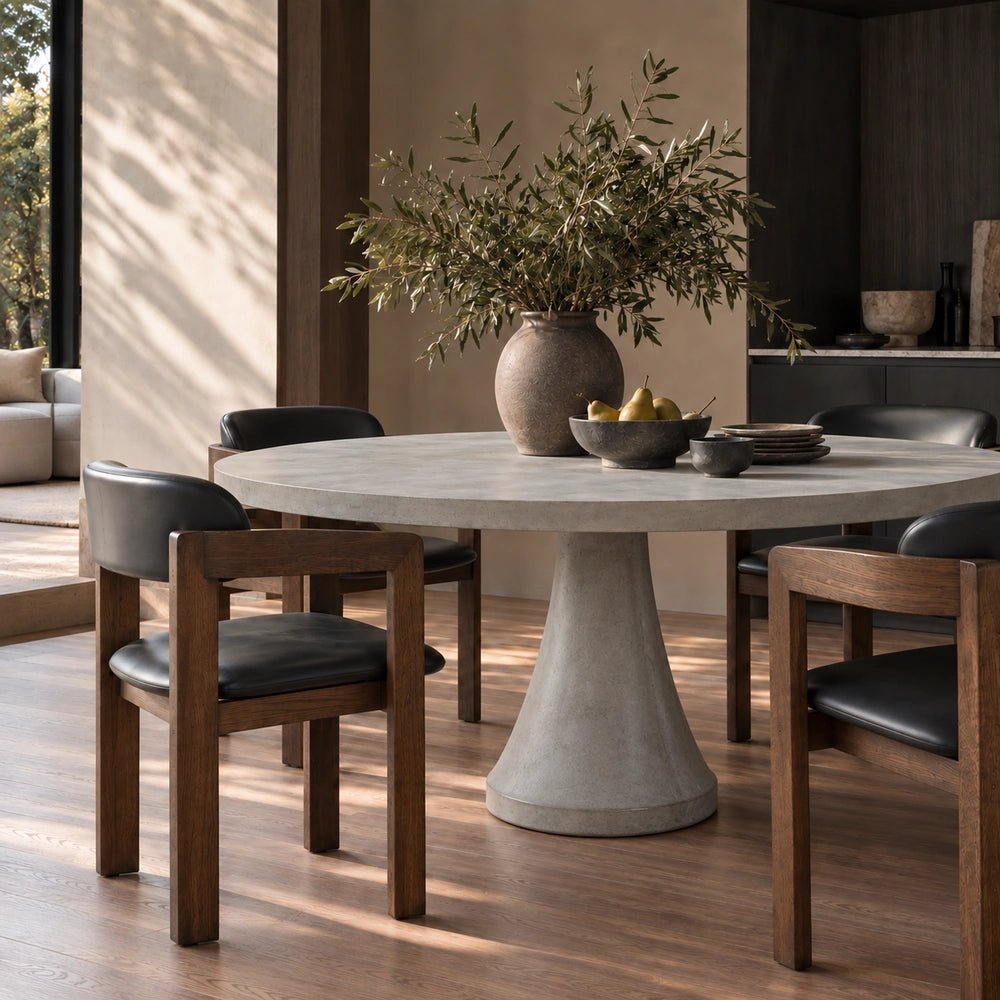 Close-up of the Datura Round Dining Table styled with dark tableware and sculptural decor, showing its textured dark finish in a contemporary dining setting.