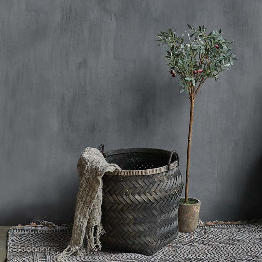 Large woven bamboo basket, with a throw draped over the side.