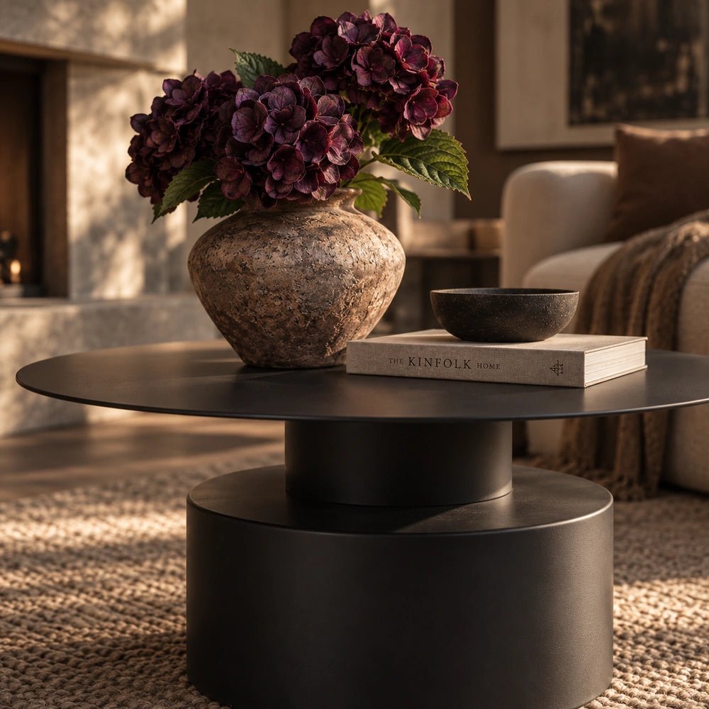 Denholm Metal Coffee Table shown from the front in a warm living room, styled with a textured vase, dark bowl, book and neutral seating.