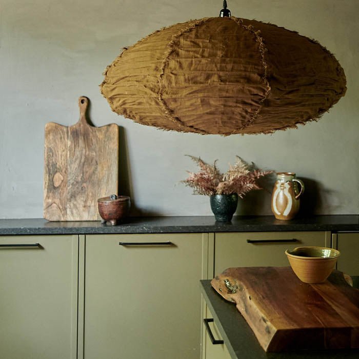 A large caramel linen shade hung low above a kitchen worktop. Linen lampshade to add a luxurious feel to your home.